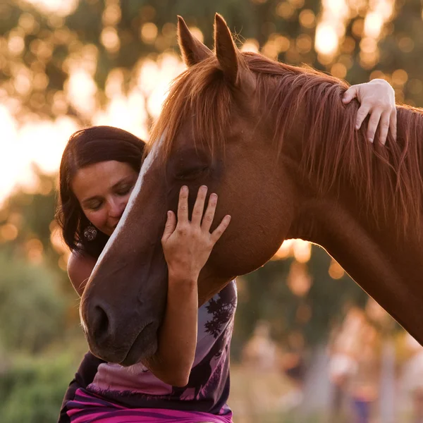 Mulheres bonitas está abraçando e beijando seu cavalo bonito — Fotografia de Stock