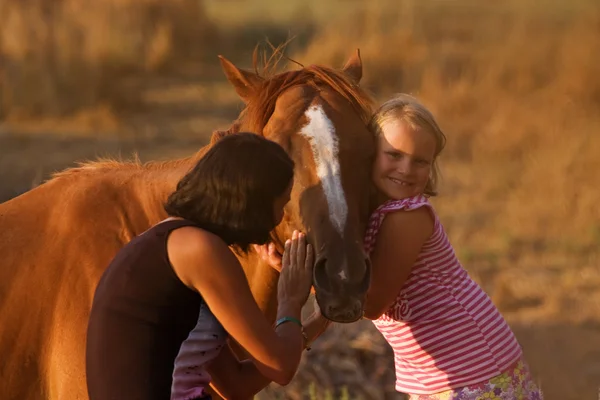 Mother and daughter feeding her handsome horse — Stock Photo, Image