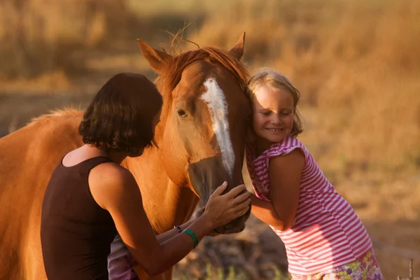 Mãe e filha alimentando seu belo cavalo — Fotografia de Stock