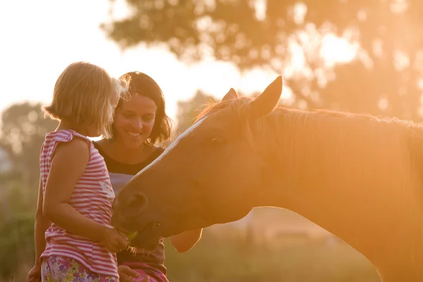 Mor och dotter utfodring hennes stilig häst Stockfoto