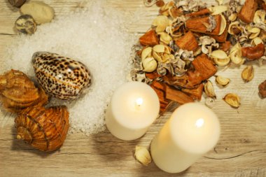 İki mum kabuğu, çakıl taşı deniz tuzu ve çiçek aromalı ahşap masa.