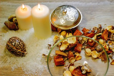 İki mum kabuğu, çakıl taşı deniz tuzu ve çiçek aromalı ahşap masa.