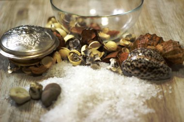 İki mum kabuğu, çakıl taşı deniz tuzu ve çiçek aromalı ahşap masa.