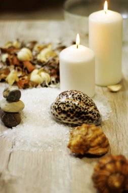 İki mum kabuğu, çakıl taşı deniz tuzu ve çiçek aromalı ahşap masa.