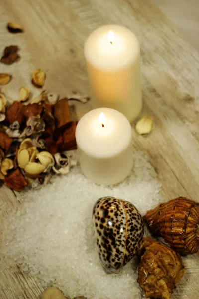 İki mum kabuğu, çakıl taşı deniz tuzu ve çiçek aromalı ahşap masa.
