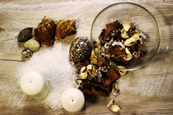 İki mum kabuğu, çakıl taşı deniz tuzu ve çiçek aromalı ahşap masa.