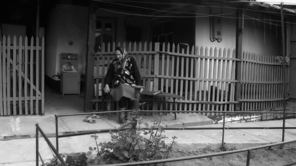 On a bench in a yard the grandmother sits — Stock Video