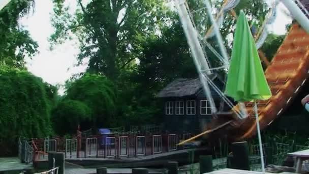 Un parc d'attractions, une grande balançoire en forme de bateau balancent doucement 