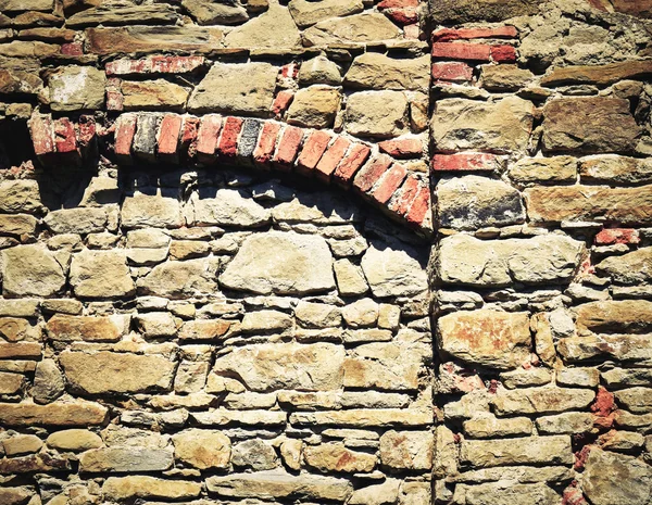 Stenen muur met bakstenen boog — Stockfoto