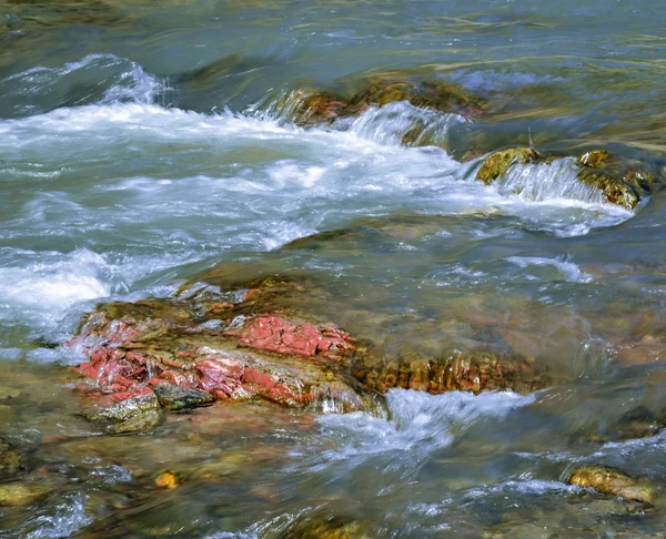 Pietra rossa in un fiume selvaggio — Foto Stock