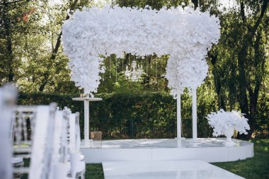 Düğün kemeri dışarıda kumaş ve çiçeklerle süslenmiş. Güzel bir düğün hazırlığı. Bahçedeki yeşil çimlerde düğün töreni. Festival dekorunun bir parçası, çiçek aranjmanı..