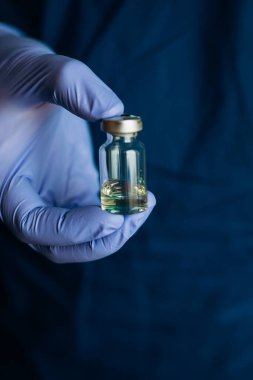 Bir doktorun elinde koronavirüse karşı bir aşı. Eldivenli eller aşıyı tutar. Covid-19 'a karşı aşı.