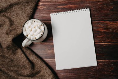 Bilgisayarın üstünde boş not defteri ve ofis tahtasının üzerinde kahve fincanı.