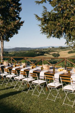 Toskana, İtalya 'da yuvarlanan tepeler manzaralı bir etkinlik için uzun bir yemek masası.