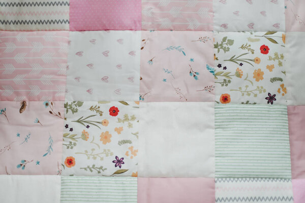 Розовое лоскутное одеяло вид сверху. Уютная детская кроватка с одеялом. Постельное белье и текстиль для детских яслей. Время сна и сна 