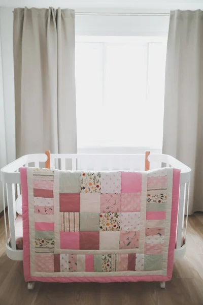 Pembe battaniyeli rahat bir bebek karyolası. Çocuk yuvası için yatak ve tekstil. Pembe ve beyaz bebek beşiğinin fotoğrafı. — Stok fotoğraf
