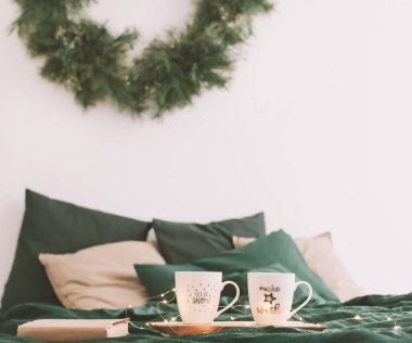 Kahve fincanları ve yatağında kitap olan rahat bir yatak odası. Noel hala hayattır. Yatakta kahvaltı. Düz yatıyordu. Tatiller, Noel konsepti