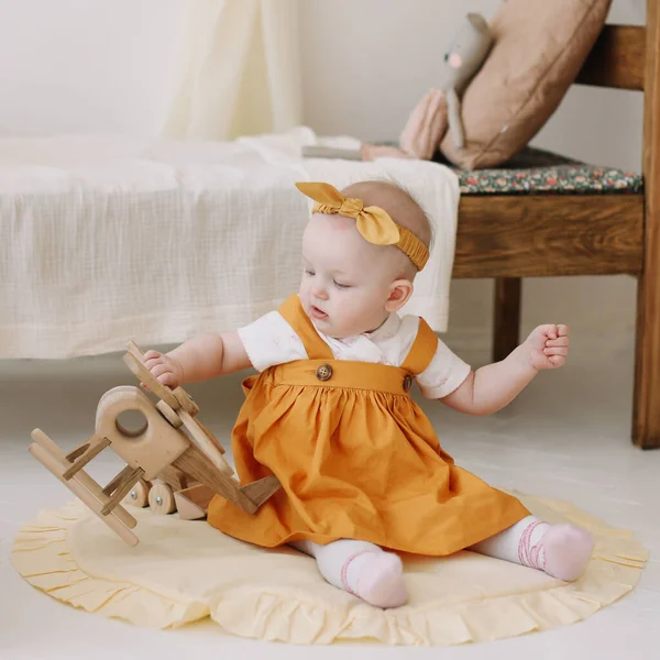 Menina bebê bonito brincando com brinquedos de madeira eco-friendly e se divertindo. Uma menina engraçada no berçário. Brinquedos livres de plástico — Fotografia de Stock