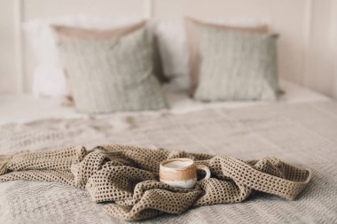 Sıcak ekoseli bir fincan kahve. Yatakta kahvaltı. Beyaz şık, rahat yatak odası. Hygge konsepti. Uzayı kopyala Düz yatış, üst görünüm.