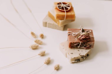 Beyaz arka planda portakal dilimleri ve çiçekli ev yapımı sabunlar. Spa konsepti, vücut bakım ürünleri. en üstteki görünüm. 