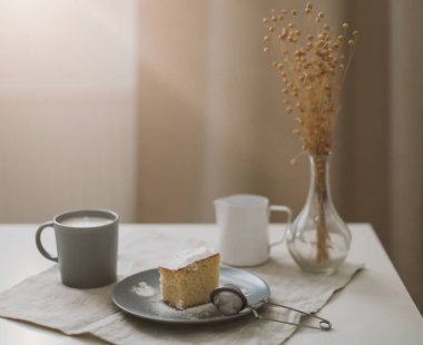Taze kek, sürahi ve bir fincan kahve. Masada bir fincan cappuccino ile bir parça ev yapımı kek. Sabah kahvaltısı