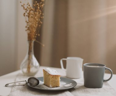 Taze kek, sürahi ve bir fincan kahve. Masada bir fincan cappuccino ile bir parça ev yapımı kek. Sabah kahvaltısı