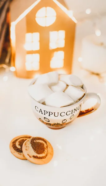 Tazza di caffè con marshmallow e biscotti su sfondo luci bokeh. Natale e Capodanno accogliente nature morte luci e decorazioni — Foto Stock