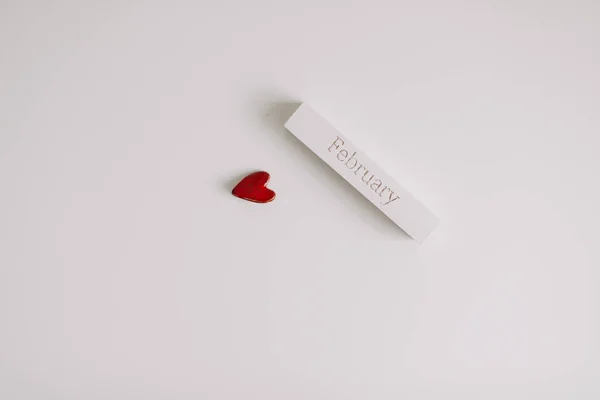 A palavra FEVEREIRO em cubo de madeira e um coração vermelho sobre fundo branco. Amor, romance, conceito do Dia dos Namorados. Flat lay, espaço de cópia — Fotografia de Stock