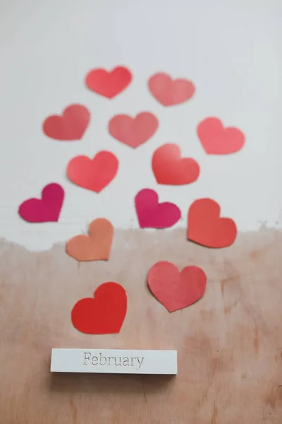 Palavra Fevereiro e corações de papel vermelho em um fundo branco. Cartão de amor romântico. Conceito do Dia dos Namorados. Deitado plano, vista superior. banner, espaço de cópia — Fotografia de Stock