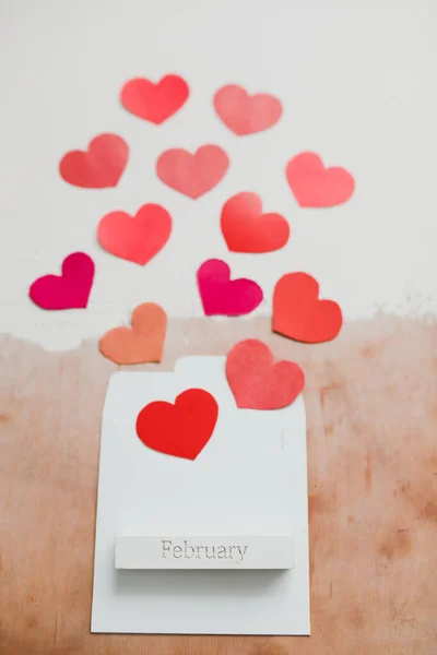 Palavra Fevereiro e corações de papel vermelho em um fundo branco. Cartão de amor romântico. Conceito do Dia dos Namorados. Deitado plano, vista superior. banner, espaço de cópia — Fotografia de Stock