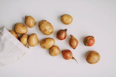 Patates ve soğan, beyaz üzerine eko-torba. organik sağlıklı gıda geçmişi. Düz konum, üst görünüm, kopyalama alanı. Market alışverişi süpermarket ve sıfır atık konsepti