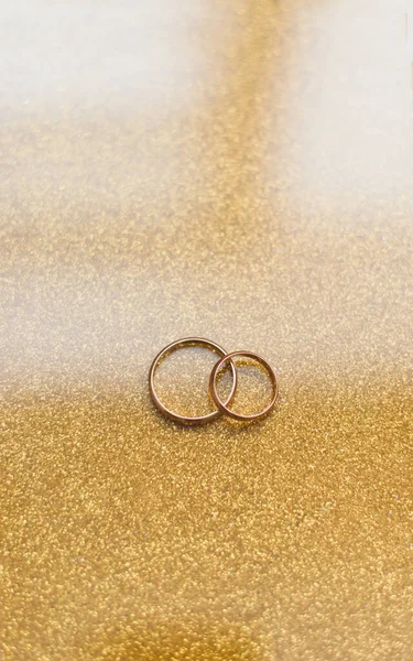 Dos anillos de boda dorados sobre un fondo dorado — Foto de Stock