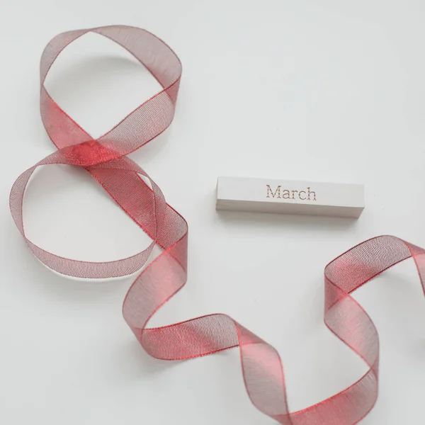 Fita vermelha e palavra MARÇO sobre fundo branco. 8 de março, Conceito do Dia Internacional da Mulher. — Fotografia de Stock