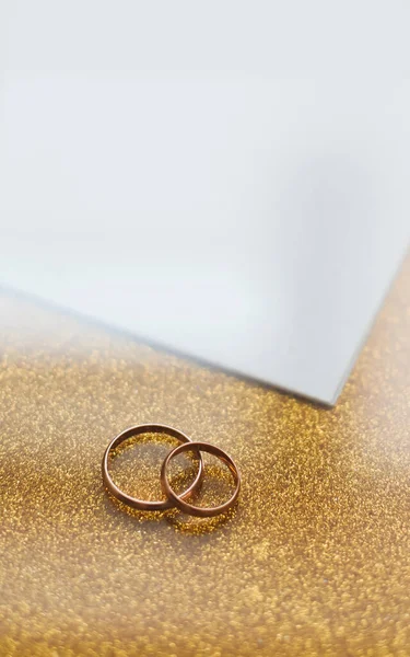 Dos anillos de boda dorados sobre un fondo dorado — Foto de Stock