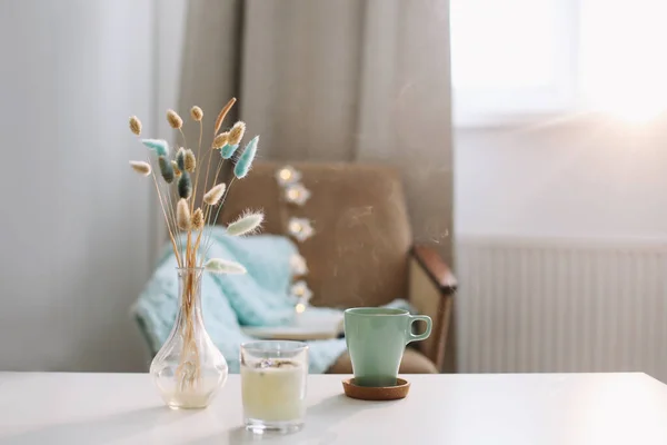 Bir fincan kahve, mum ve kahve masasında çiçekler olan bir vazo ile yaşam tarzı kompozisyonu. Konforlu ev dekorasyonu konsepti