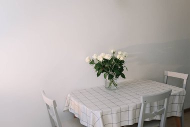 Beyaz masadaki cam vazoda taze beyaz güller..