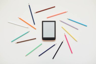 dijital tablet ve beyaz arkaplanda renkli kalemler