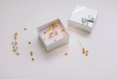 Çiçeklerin arka planında altın nişan yüzüğü olan bir kutu. Düğün, evlilik teklifi konsepti. 