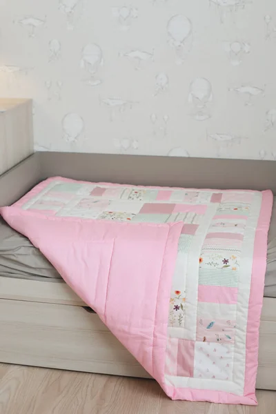 Gemütliches Babybett mit rosa Patchwork-Decke. Bettwäsche vorhanden. Bettwäsche und Textilien für Kinderzimmer. Mittagsschlaf und Schlafzeit — Stockfoto