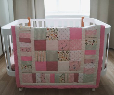 Pembe battaniyeli rahat bir bebek karyolası. Bebek yatağı. Çocuk odası için yatak ve tekstil. Uyku ve uyku zamanı.