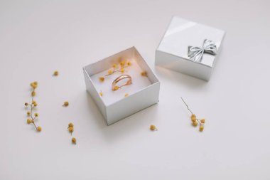 Çiçeklerin arka planında altın nişan yüzüğü olan bir kutu. Düğün, evlilik teklifi konsepti