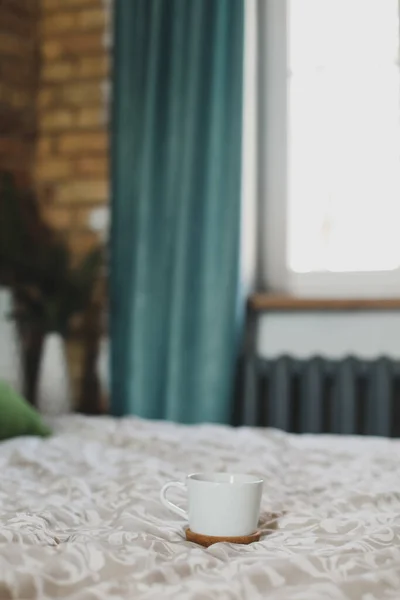 Copo de café branco na cama. Bom dia, pequeno-almoço na cama conceito. — Fotografia de Stock