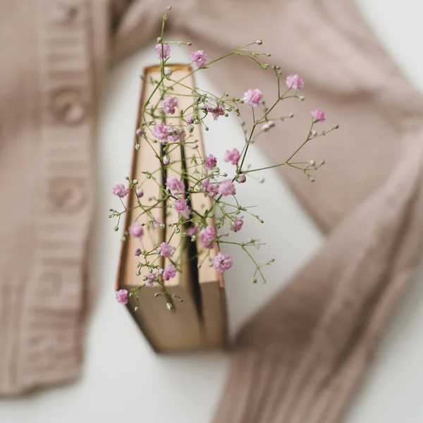 Warm knitted sweater and a book with flowers at white background. Cozy vintage. Flat lay, top view — Stock Photo, Image