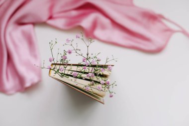 İçinde çiçekler ve pembe ipek kumaş olan romantik bir kompozisyon. Düz yat, üst görünüm, maket yap.