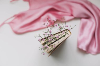 İçinde çiçekler ve pembe ipek kumaş olan romantik bir kompozisyon. Düz yat, üst görünüm, maket yap.