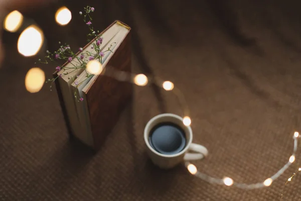 Um livro com flores e xícara de café no fundo escuro vista superior — Fotografia de Stock