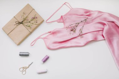 Pembe ipek kumaşlı kompozisyon, el işi kağıt, iplik ve makas şeklinde beyaz arka planda hediye. Düz yerde, üst tarafta. Hobi, eğlence konsepti.