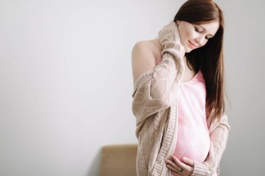 Uzun siyah saçlı hamile bir kadının portresi.