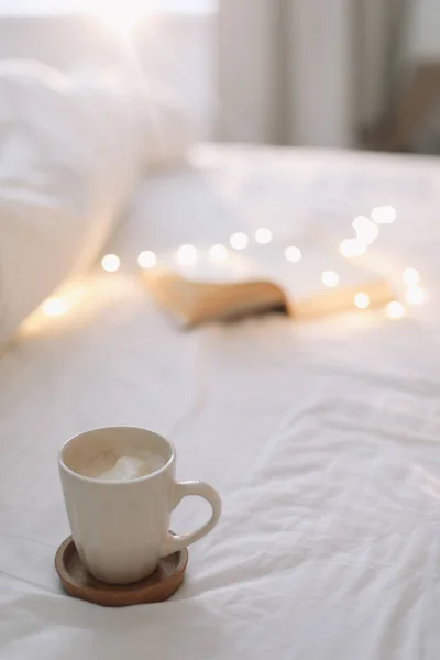 ベッドシートとコーヒーのカップに本を開きます。おはようございます。ベッドで朝食。平置き — ストック写真