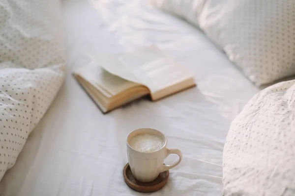 Libro aperto sulle lenzuola e una tazza di caffè. Buongiorno. Ciao. Colazione a letto. posa piatta — Foto Stock